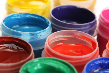 jars with multicolored gouache on white background close-up
