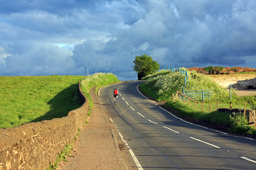 Beautiful Scottish road with a lonely cyclist in the countryside