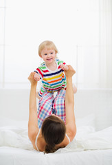 Fototapeta premium Mother playing with baby in bedroom