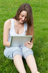 Young girl with tablet sitting on lawn.