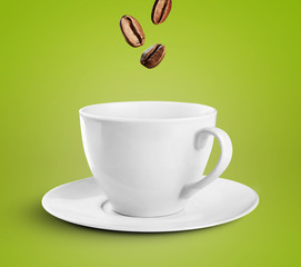 Coffee cup on green background with coffee beans falling into it