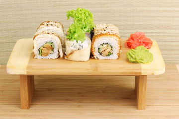 Tasty rolls served on wooden plate on wooden background