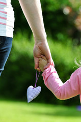 Mutter hält Kinderhand mit Herz