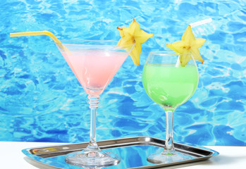 Glasses of cocktails on table on blue sea background