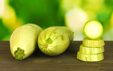 sliced squash on wooden table on green background