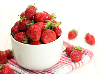 sweet ripe strawberries in bowl on white wooden table