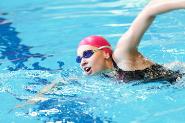 Fototapeta na wymiar Młoda dziewczyna pływa freestyle w basenie
