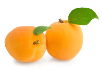 Two ripe apricot with a leaf on a white background