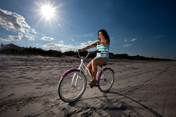 Young Brunette Woman riding bike on Beach