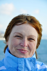 Portrait of 55-aged woman on the blue sky background