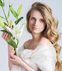 Beautiful young woman with white lily on background