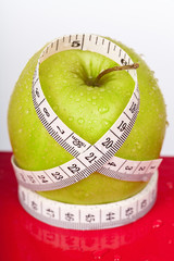 green and wet apple with measure tape