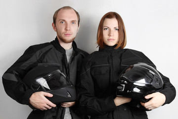 young motorcyclists man and woman holding helmets in studio