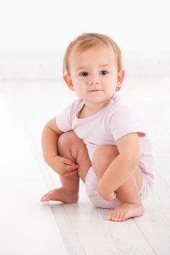 Cute baby girl crouching on floor