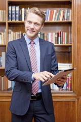Mann in Bibliothek mit Tablet PC