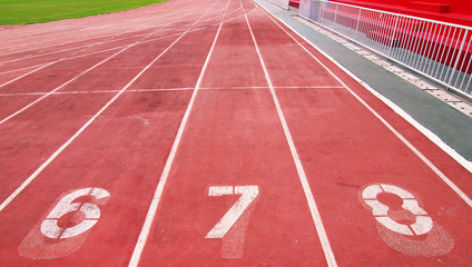 Lanes of a red race track with numbers and red seats in the stad