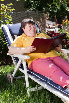 behinderte Frau liest ein Buch im Garten
