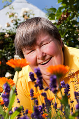 behinderte Frau liegt auf Wiese und riecht an Blumen