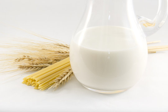 Milk in the pitcher, spaghetti, corn ears on white background