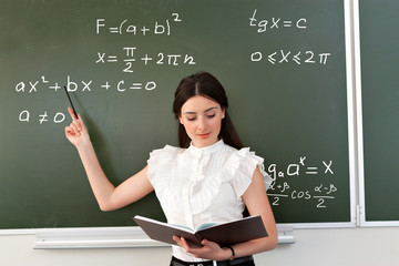 smiling teacher writes on blackboard