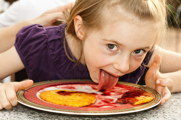 Girl eating potato pancakes with strawberry syrup