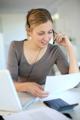 Young woman working from home with laptop and headset