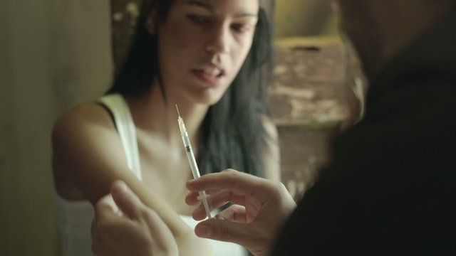 Drugs and people, man helping woman with heroin syringe