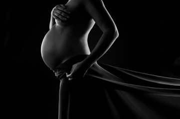 Pregnant woman in silk veil demonstrating her belly