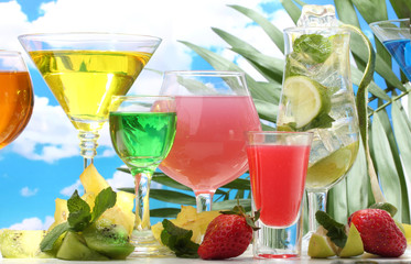 Glasses of cocktails on table on blue sky background