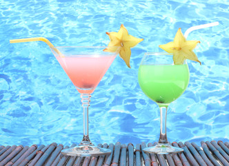 Glasses of cocktails on table on blue sea background