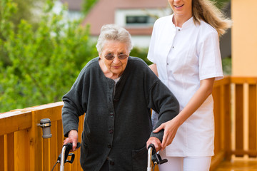 Alter und Pflege - Pflegerin und eine Seniorin mit Rollator