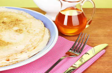 Stack of tasty pancakes on wooden table on green background