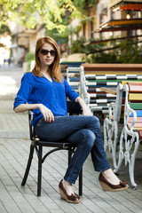Style redhead girl sittin in the chair in the cafe