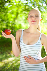 young beautiful fit and healthy woman holding an apple and smili