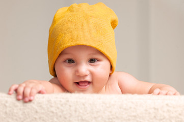 Cute Baby With A Beanie Hat Behind A Sofa