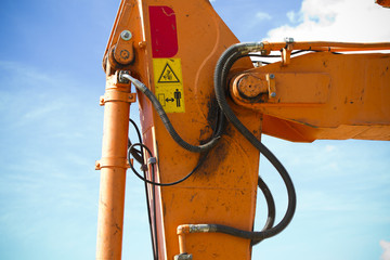 Orange tractor on blue sunrise sky, crane detail