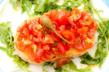 Fresh bruschetta with tomato, basil and caper.