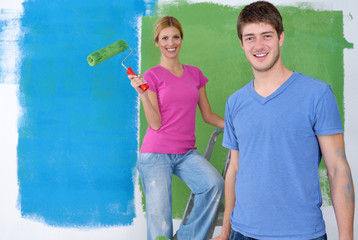 happy couple paint wall at new home