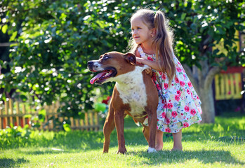 Cute four-year old girl playing with her dog