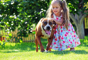 Cute little girl playing with her Staffordshire terrier dog