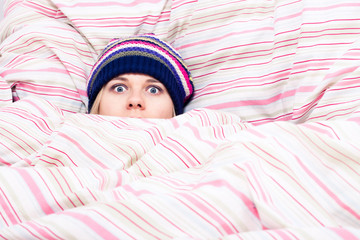 Scared woman hiding in duvet