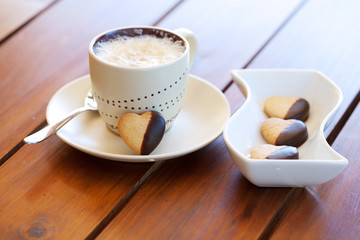 Freshly baked heart-shaped cookie and cappuccino