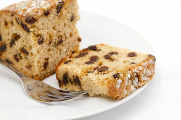 Fruit cake sliced on white plate with fork