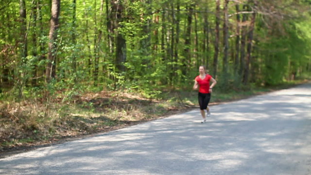 Young woman jogging in the forest, slow motion, dolly shot