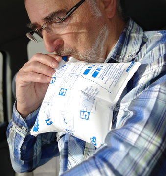 homme senior soufflant dans un &eacute;thylotest