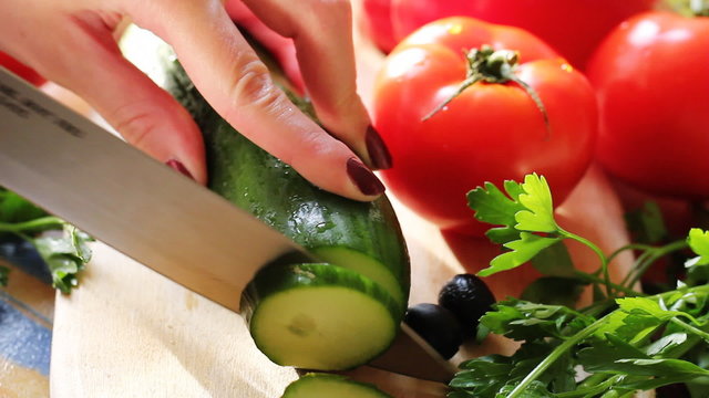 Woman's hands cutting cucumber