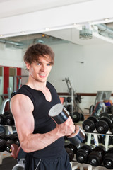 Sport - Mann trainiert mit Hanteln im Fitnessstudio