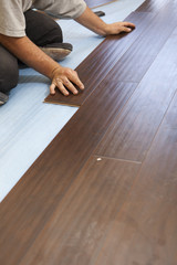 Fototapeta na wymiar Man Installing New Laminate Wood Flooring