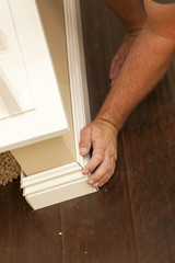 Contractor Fitting New Baseboard to Wall and New Laminate Floori