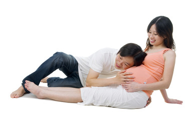 Asian man listening to pregnant wife's belly